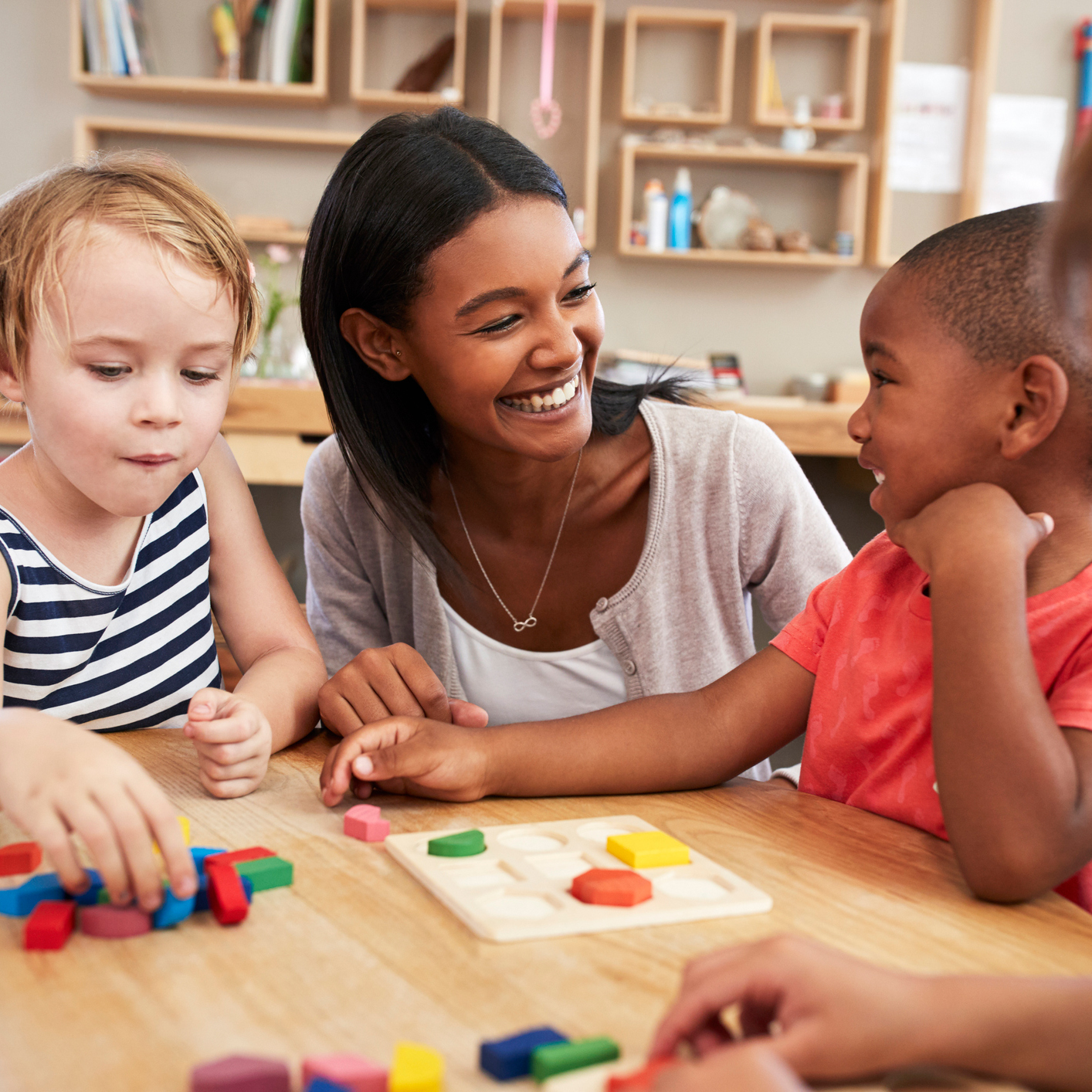 Teacher smiling at two young children