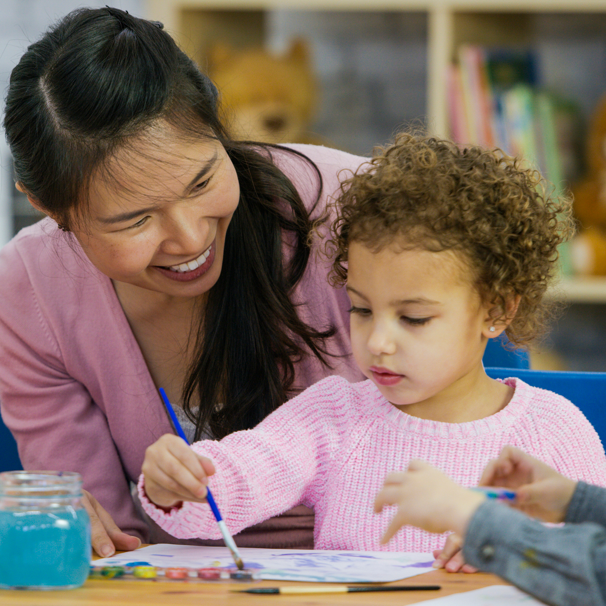 Teacher watching young child paint