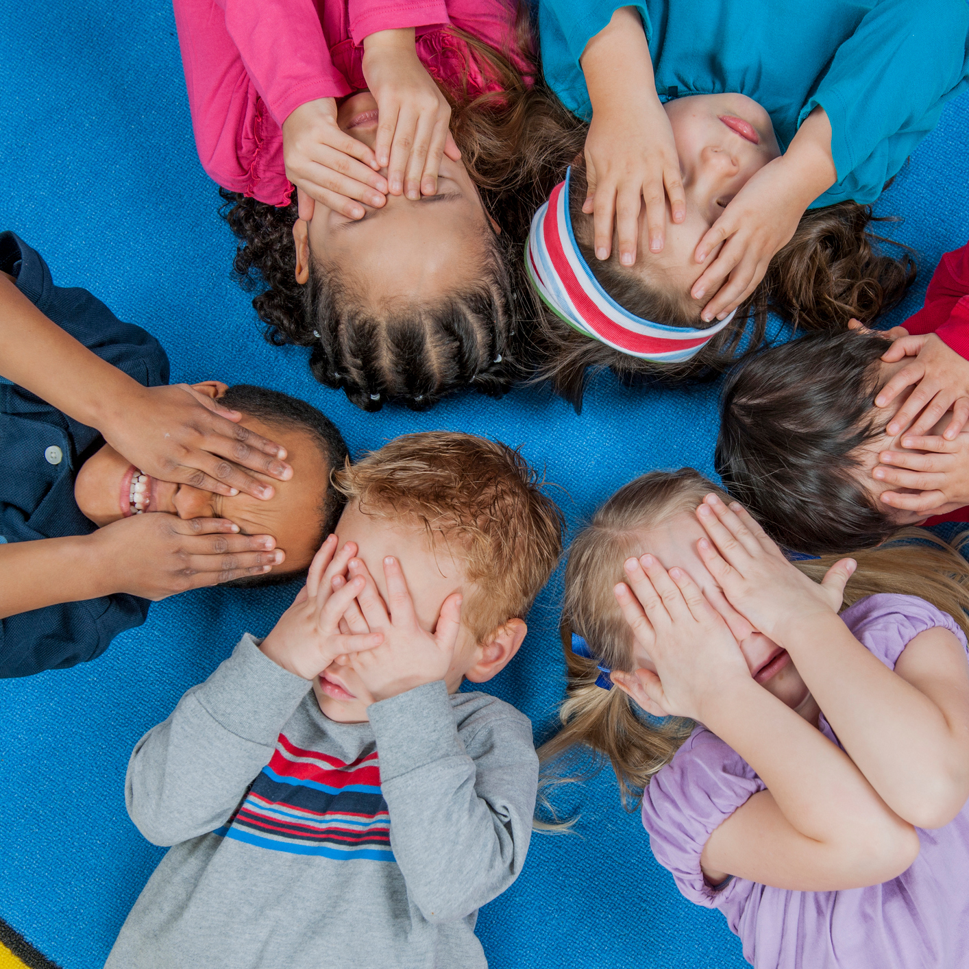 Circle of children covering their eyes