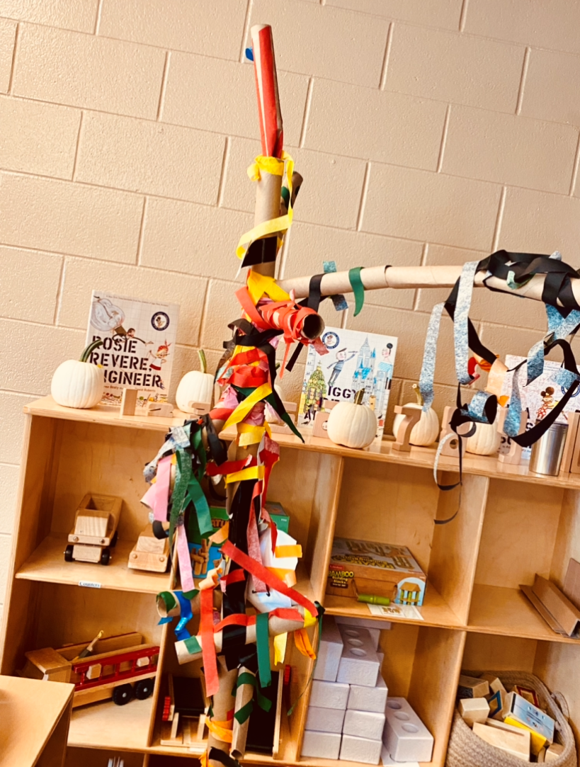 Children's construction of a tree from colorful tape and paper towel rolls. 