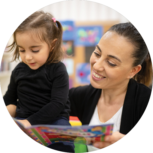 A teacher reads a book with a child.