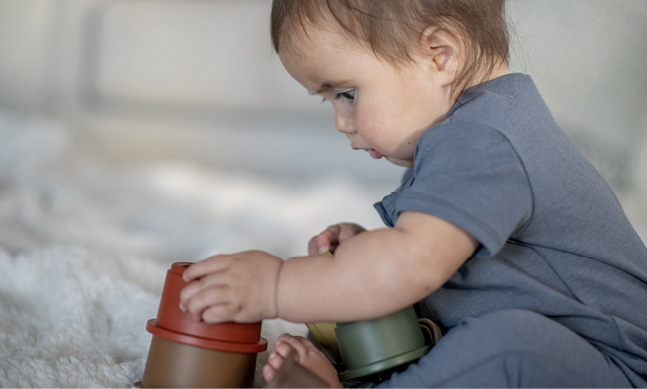 A baby explores stacking cups.