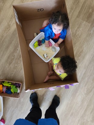 A toddler investigates cornstarch and water while sitting in a box.