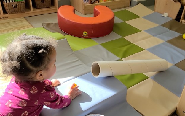 A toddler plays with a ramp.