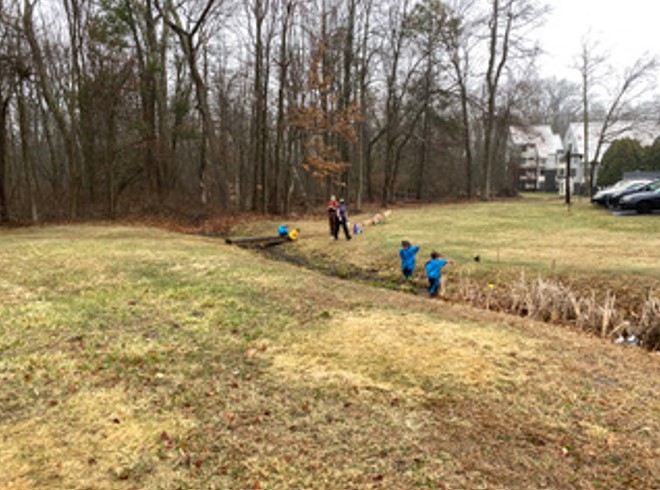 Toddlers run to the outdoor stream.