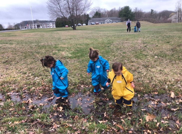 Toddlers watch their boots disappear in the water.