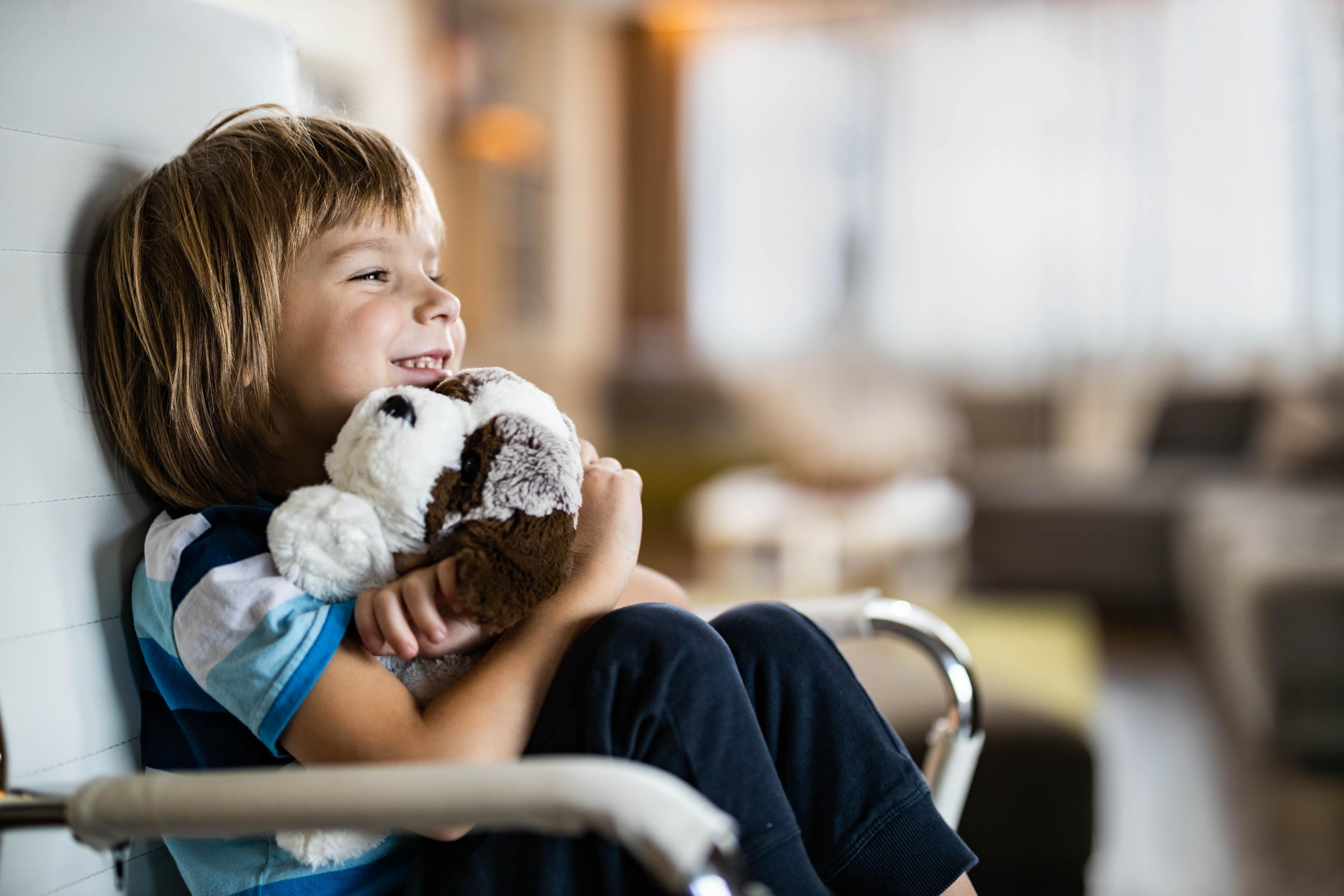 A child hugs a stuffed animal in the comfort corner.