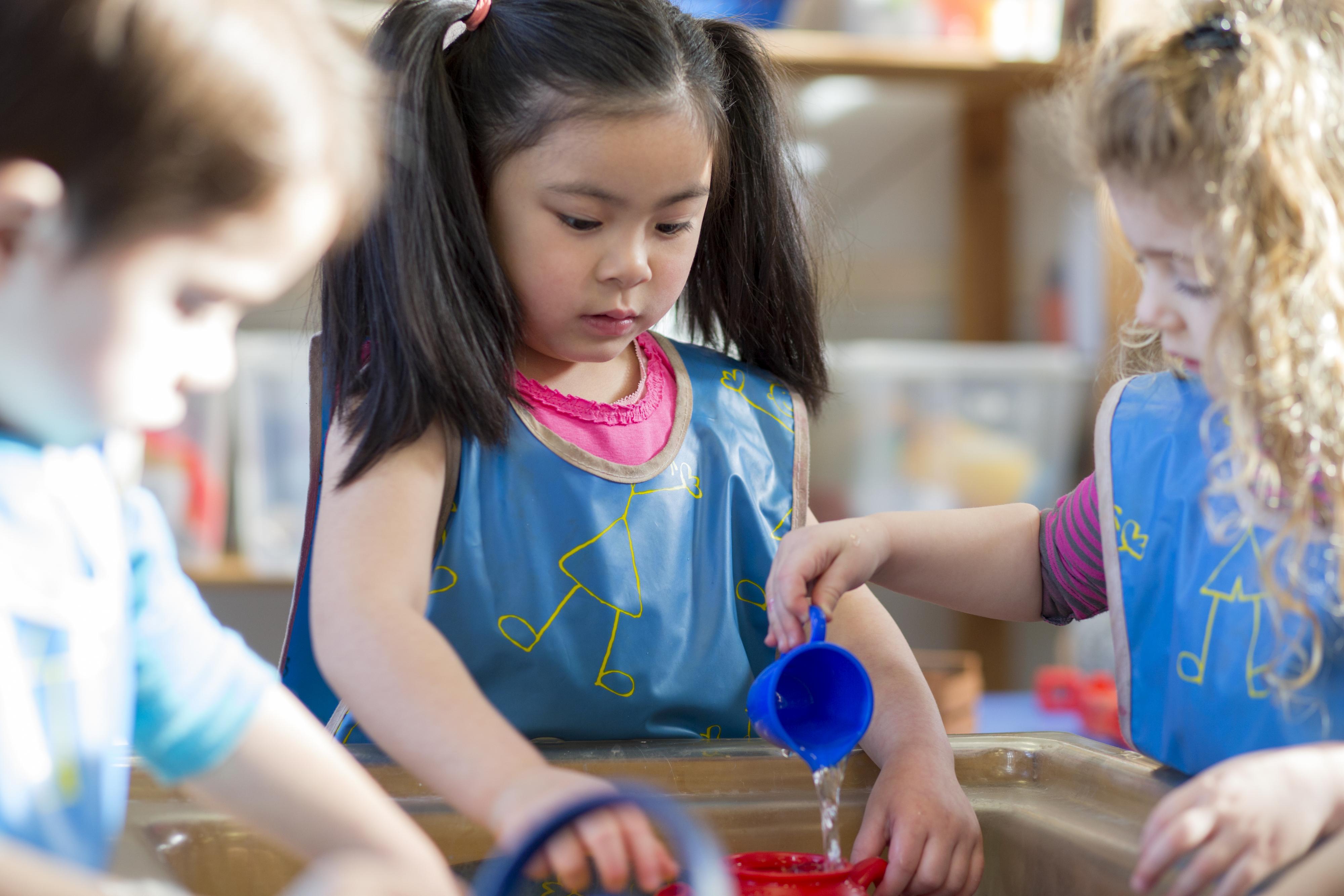 Children exercise self-control and compromise when working at the water table.