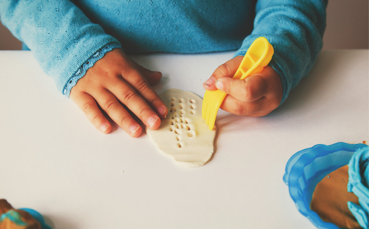 Plasticine modeling clay. Child dough play in school mold from plasticine  in kindergarten. Kids knead modeling clay with hands in preschool.  Preparation for exhibition of crafts made of plasticine. Stock Photo