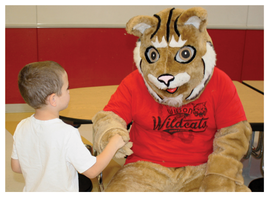 One young student shaking hands with a wildcat mascot