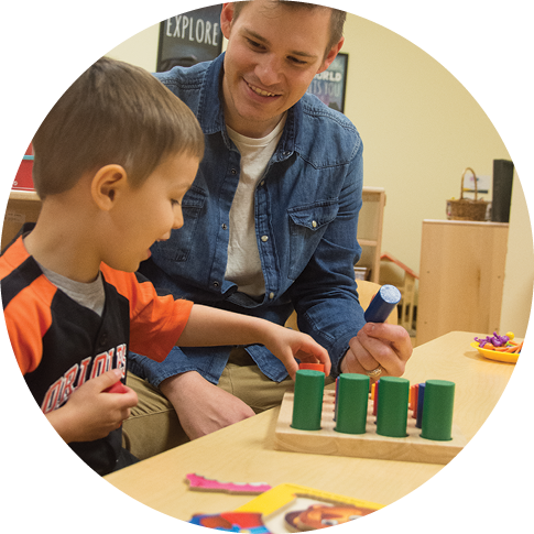 Bryson McCargar playing with cylindrical blocks with one of his students