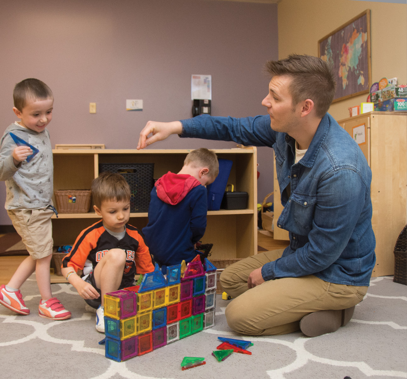 Bryson McCargar playing with magnatiles with three male students on the floor of the classroom