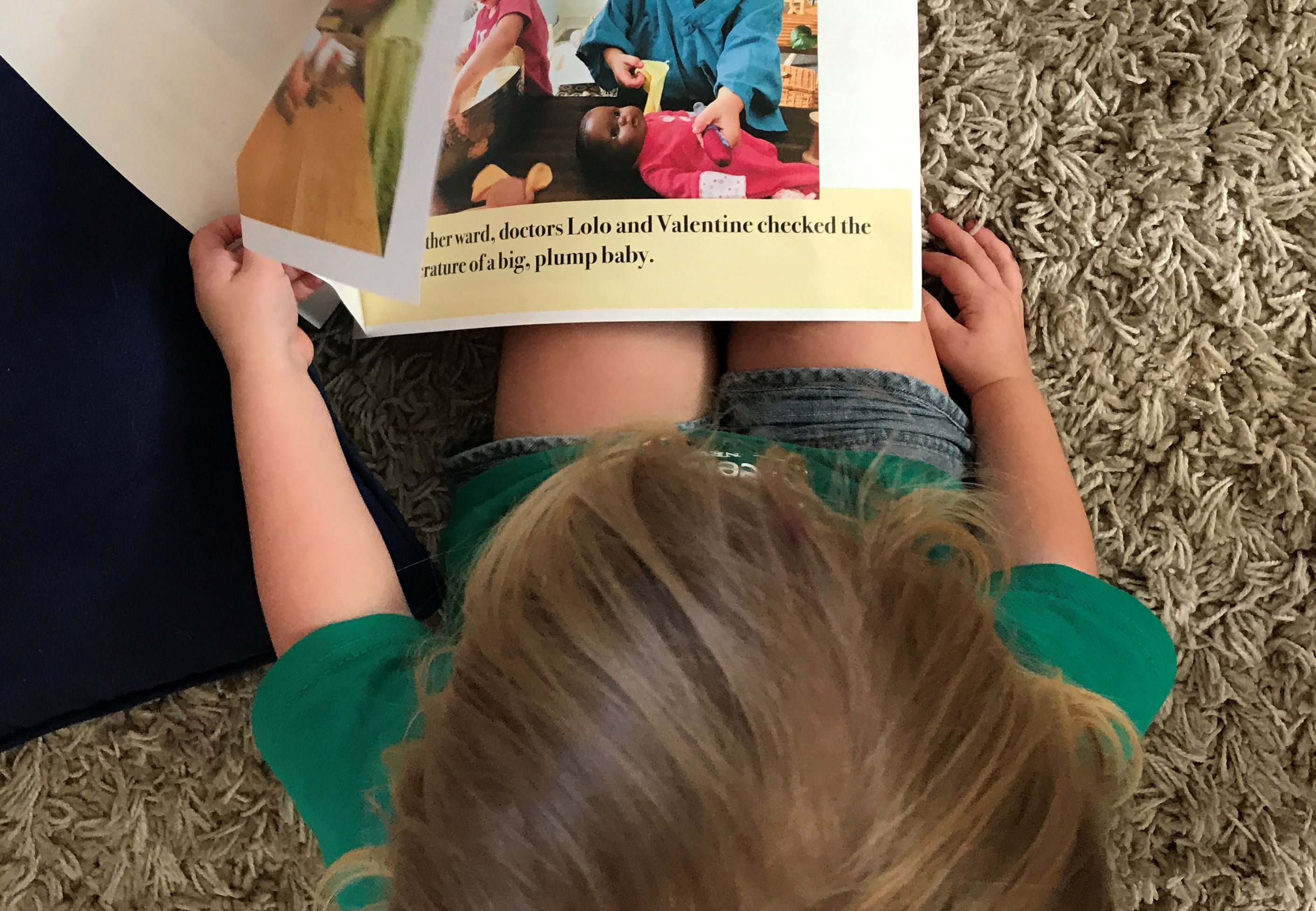 A child looks at the play story booklet about doctors and babydolls.