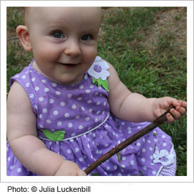 Young infant smiling in purple dress