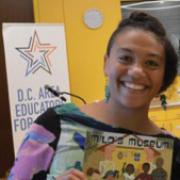 Megan Pamela Ruth Madison holding a children's book and smiling.