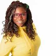 Picture of woman with glasses, braids, in a yellow shirt