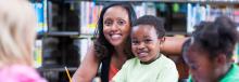 Woman and son sitting in the library smiling.