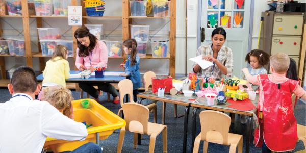 Two toddler teachers assisting play centers in classroom
