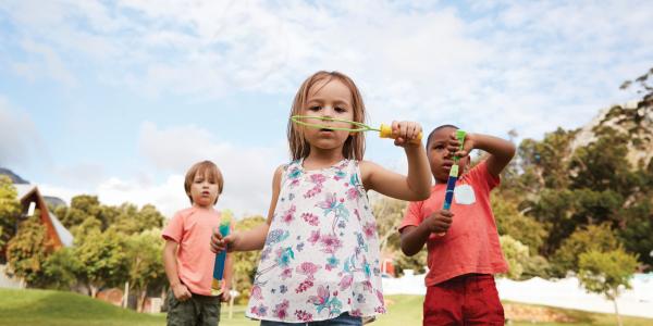 Children blowing bubbles in field