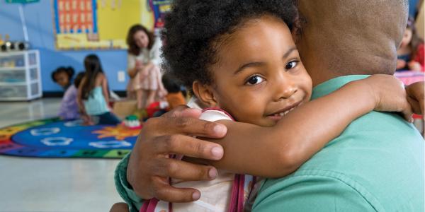 Girl hugging father in classroom