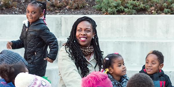 African-American teacher with kindergarten students sitting outside