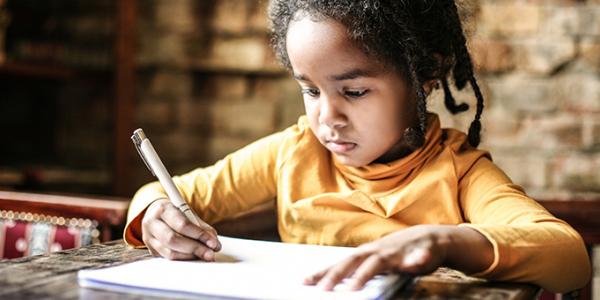 Young girl writing at a desk at home