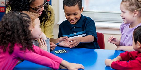 Teacher guiding preschool students at table