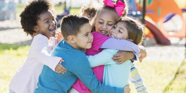 Preschoolers hugging on a playground