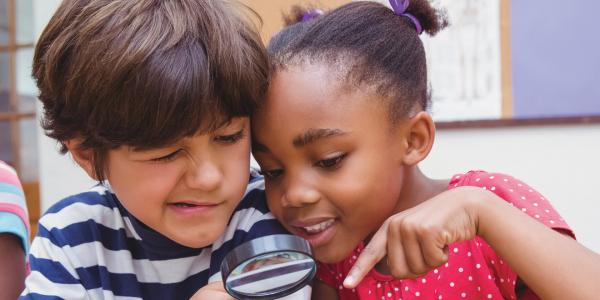 Two children looking through magnifying glass