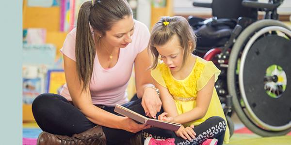 Teacher and student with a disability reading a book together