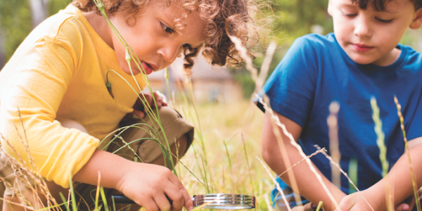 Two kids looking through magnifying glass