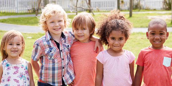 Preschool age children pose for a picture outdoors.