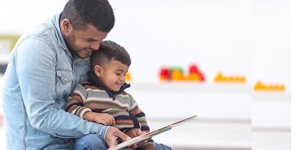 A young child reading a book with a parent