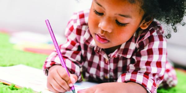 A young child writing in a book