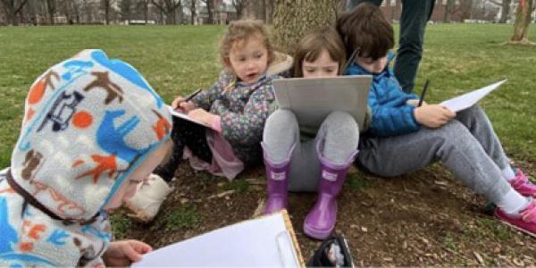 A group of young children sitting outside drawing