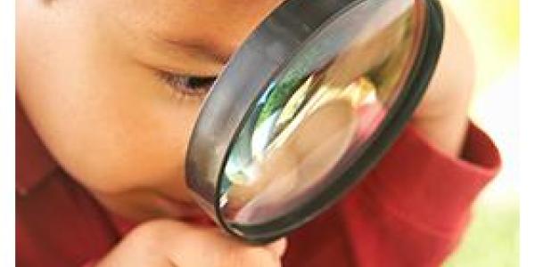 Boy with magnifying glass looking at the grass