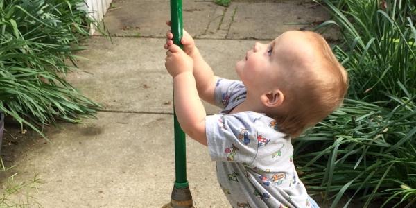 Toddler holding a broom outside