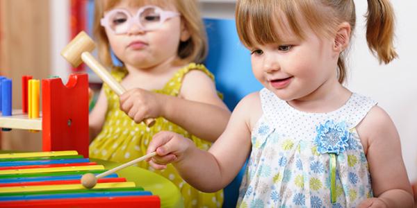 Two young girls playing with a xylophone