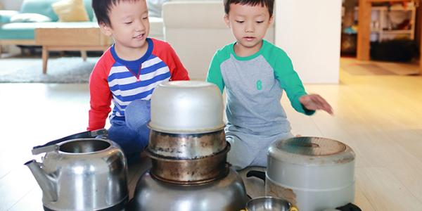 Two boys playing with pots on the kitchen floor