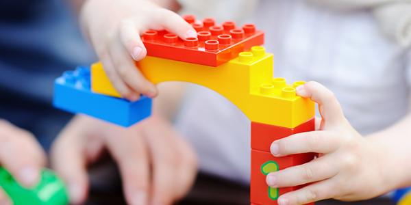 Parent and child's hands building with legos