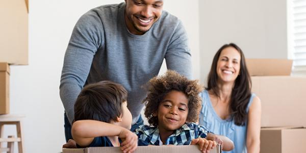 Two young boys playing in a box with mother and father smiling behind them