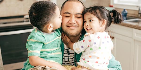 Father hugging toddler son and daughter