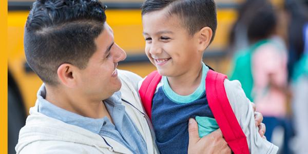 Father and son hugging by the school bus