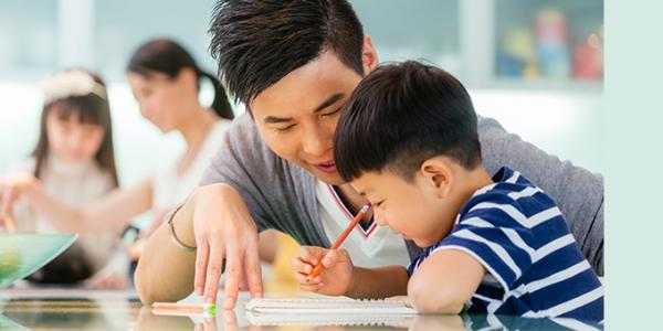 Preschooler and father writing at desk