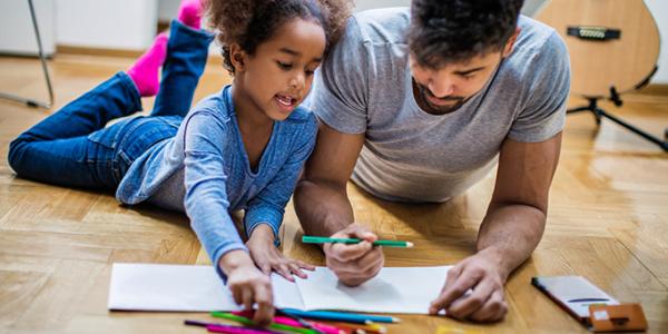 Father and daughter talking and coloring on the floor