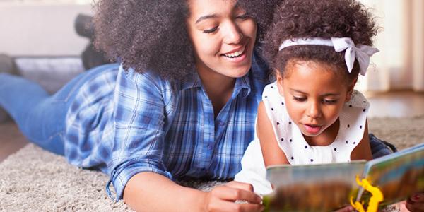 Toddler reading book with mother