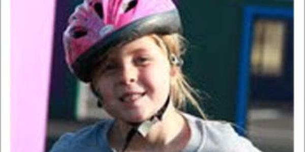 Young girl on a bike wearing a pink helmet