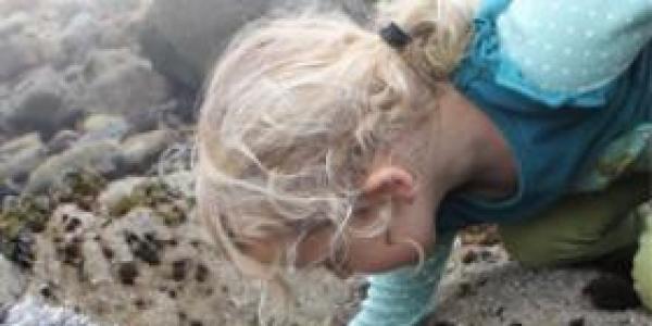 Young girl exploring rocks by the sea