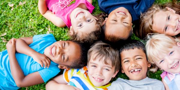 Seven children outside on the grass.