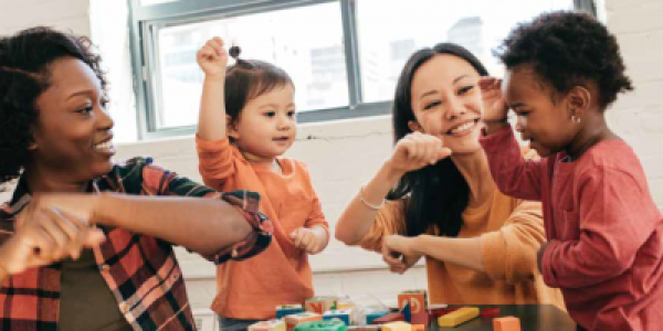 Two adults at a table playing with two toddlers.